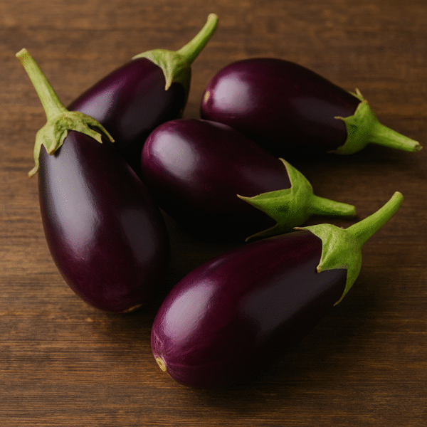 A group of glossy purple brinjals (eggplants) with green stems arranged on a rustic wooden background, showcasing their freshness and export quality.