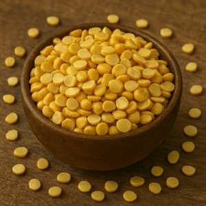 A wooden bowl filled with Chana Dal (split Bengal gram) placed on a rustic wooden background, with yellow lentils scattered around the bowl for a natural, earthy look.