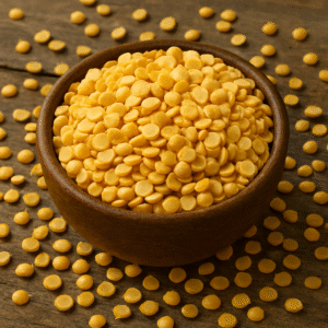 A wooden bowl filled with yellow Toor Dal (split pigeon peas) placed on a rustic wooden background, with scattered lentils creating a natural and organic look.